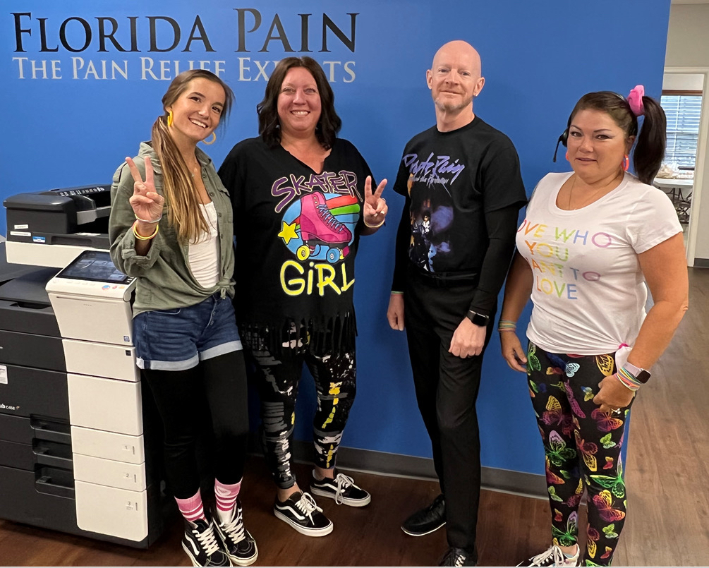 Florida Pain Staff in 80s clothes smiling at the camera, two holding up peace sign