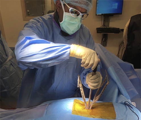 A doctor in mask and scrubs performs a surgical procedure on a patient