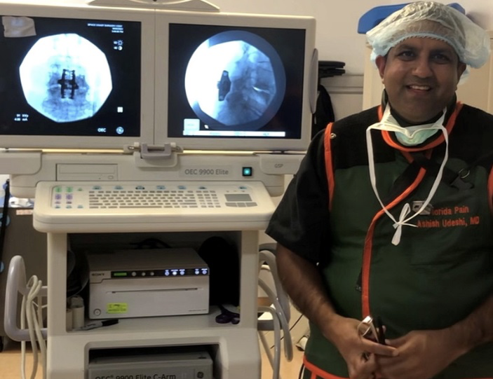 Dr. Udeshi smiles while standing near surgical camera equipment